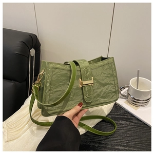 Detail view of the green pleated leather baguette bag with a stylish gold buckle