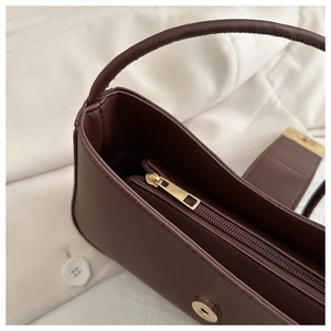 Detailed close-up of dark brown leather handbag with gold metal zipper and inner pocket
