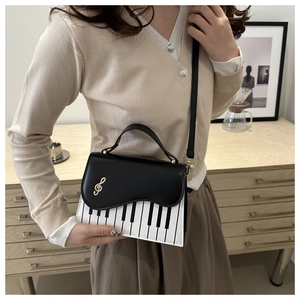 Detail of piano keyboard pattern handbag with golden musical note clasp on a crossbody bag