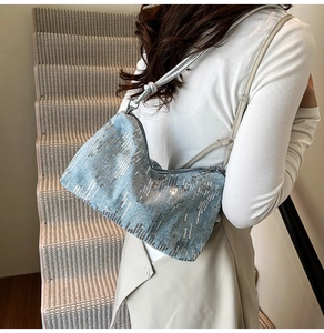 Detail of light blue sequined shoulder bag with silver leather strap on model