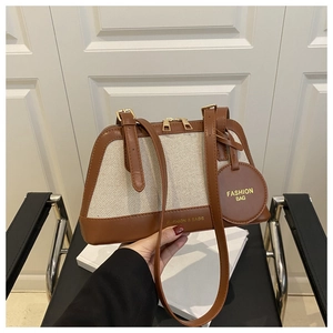 Detail of canvas tote bag showing brown leather trim, zipper, and matching mini pouch charm