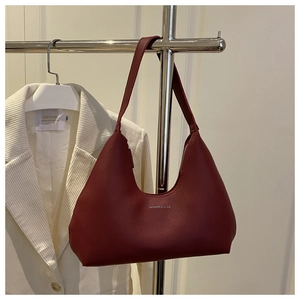 Detailed view of a wine red matte leather shoulder bag hanging on a metal rack