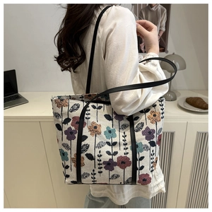 Close-up of floral jacquard tote bag with black leather straps and colorful flower patterns
