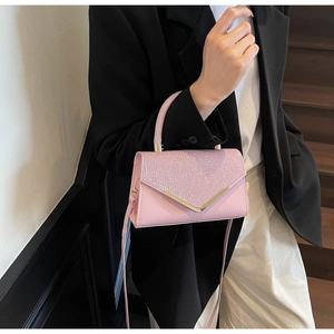 Detail of pink sequin crossbody bag with V-shaped gold buckle and smooth leather texture