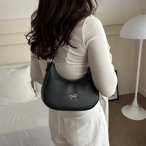 Detailed shot of a black hobo bag featuring a silver metal bow accent and leather texture