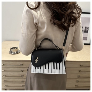Detail of artistic piano key pattern and gold G-clef on a black and white crossbody bag