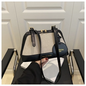 Detail of canvas and black leather tote bag with metal zippers on a black chair