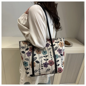 Detail of vintage floral knit tote bag with black leather shoulder straps on a model