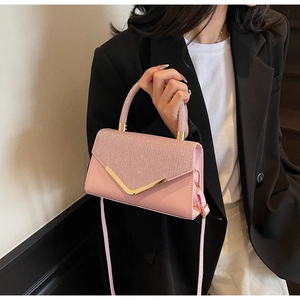 Detail of pink rhinestone handbag featuring golden V-shaped metal hardware and top handle