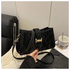 Detail of black pleated leather baguette bag featuring a gold H-shaped hardware buckle