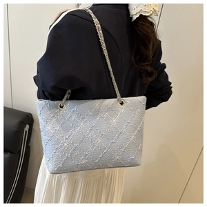 Détail du sac cabas bleu clair avec broderie florale et chaîne en métal porté par mannequin