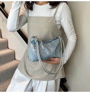 Detail of light blue denim underarm bag with silver sequins and metallic rope handle
