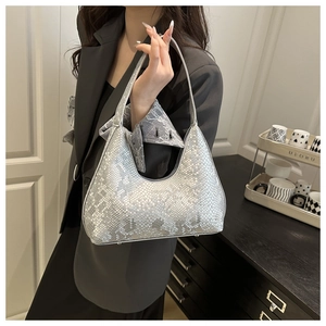 Detail of silver snake-patterned half-moon bag worn by a model in a minimal setting