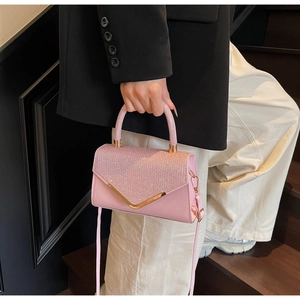 Pink crossbody bag featuring a sequined flap and elegant V-shaped gold metal trim detail