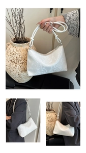 Detail of white snakeskin texture handbag with unique knotted strap and zip closure