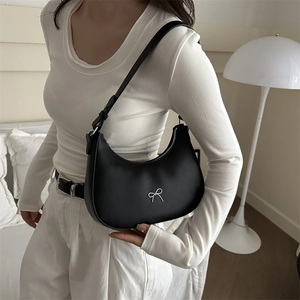 Detail of a black crescent hobo bag featuring a silver bow metal accent and adjustable strap