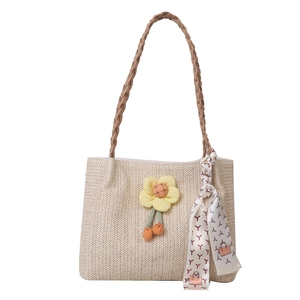 Woven straw tote bag in beige with brown handles, yellow daisy charm, and silk scarf