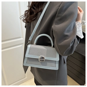 Détail du sac bandoulière bleu clair avec rabat tissé et fermoir métallique argenté