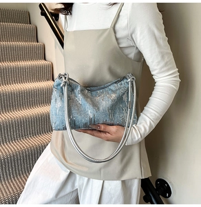 Detail of light blue sequined underarm bag with silver leather straps and metal zipper