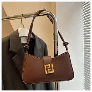Detail view of brown leather baguette bag with gold metal buckle and knotted strap