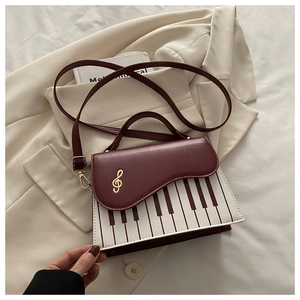 Detail of piano key pattern handbag with a golden treble clef clasp and burgundy flap