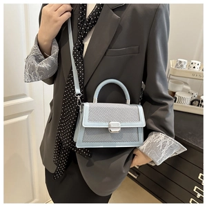 Détail du sac bandoulière bleu clair avec texture tressée et fermoir en métal argenté élégant