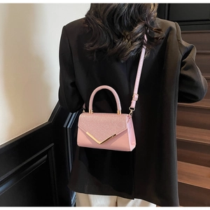 Pink glitter leather shoulder bag with gold V-metal buckle worn with a black blazer