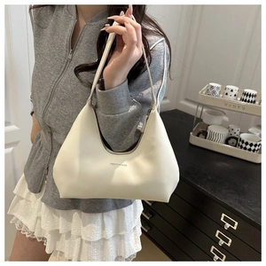 Detailed side view of a cream-colored half-moon underarm bag with smooth faux leather texture
