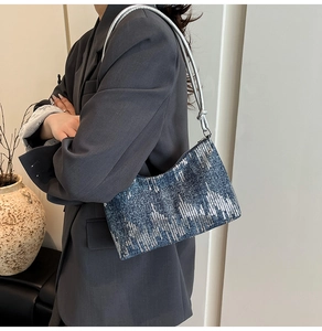 Detail of navy blue sequined shoulder bag showing silver knot strap and texture