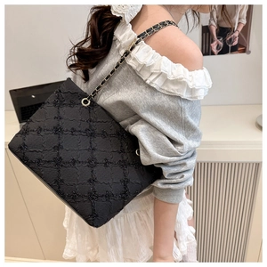 Détail de la texture matelassée noire et de la bandoulière en chaîne dorée du grand sac cabas