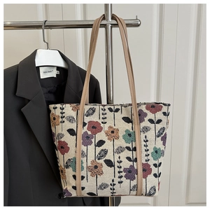 Detailed close-up of vintage floral jacquard fabric and brown leather straps on tote bag
