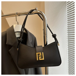Detail view of black leather baguette bag with golden metal buckle and knotted strap accents
