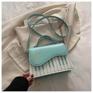 Detail of mint green handbag with piano key print and gold musical note embroidery