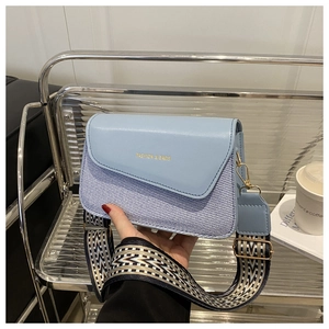 Close-up of light blue shoulder bag with woven texture and geometric jacquard strap