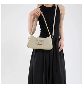 Detail of champagne woven handbag featuring a silver bow buckle and detachable strap