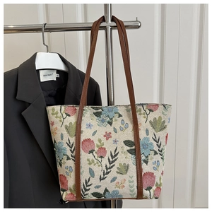 Close-up of the tapestry woven floral pattern and brown leather straps on the tote bag