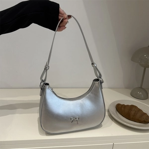 Close-up of a metallic silver hobo bag with an elegant bow accent and smooth zipper