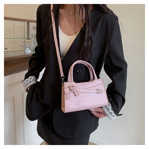 Close-up of pink crossbody bag with decorative bow and straps worn by a model