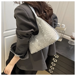 Detail of silver snake-pattern underarm bag on shoulder with sleek crescent shape