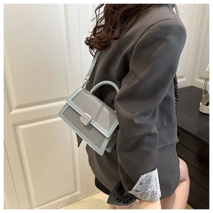 Mannequin portant un petit sac bandoulière bleu clair avec texture tissée et fermoir