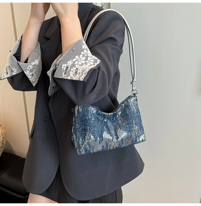 Detail of blue denim shoulder bag with silver sequins and metallic strap on model