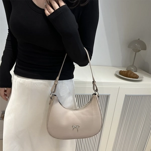 Detail of apricot hobo bag with silver metal bow accent and smooth matte finish