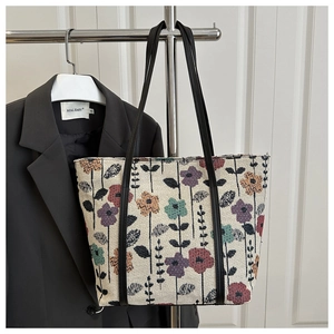 Detail of vintage floral jacquard tote bag with black leather straps on a dark suit