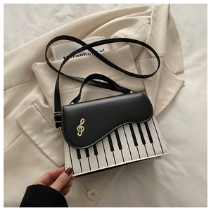 Close-up of piano key patterned crossbody bag with gold treble clef accent and leather strap
