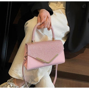 Close-up of pink sequined handbag showing the gold V-shaped buckle and fine texture