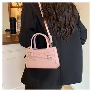 Detailed view of pink bow square bag with adjustable strap worn on black blazer