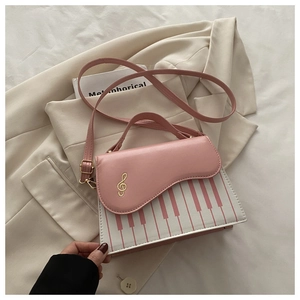 Close-up of piano key pattern and gold treble clef detail on a pink crossbody handbag