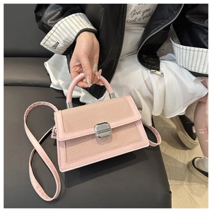 Gros plan d'un sac bandoulière rose avec texture tressée et fermoir métallique