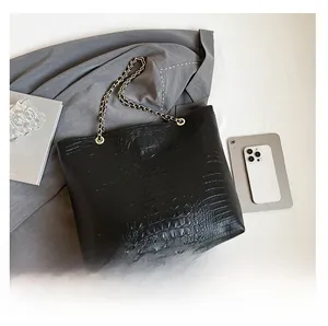Detailed top view of crocodile pattern tote bag with gold chain strap on stylish desktop