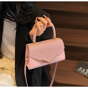 Detail of pink crossbody bag with sparkling rhinestones and golden V-shaped metal hardware